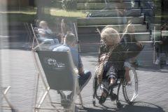 Na zdjęciu dwie rozmawiające osoby, jedna na leżaku druga na wózku inwalidzkim.